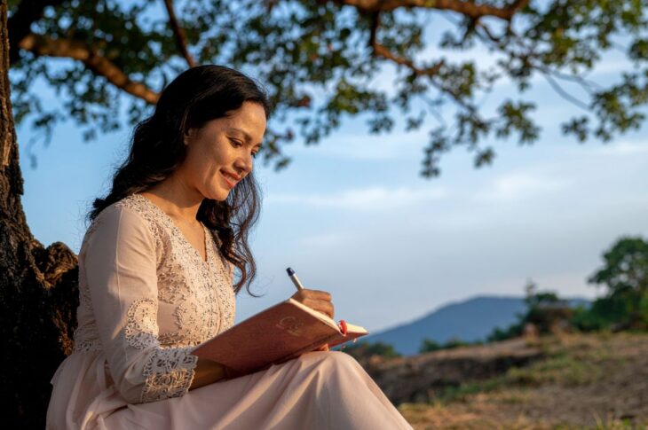 Woman writing in journal outdoors