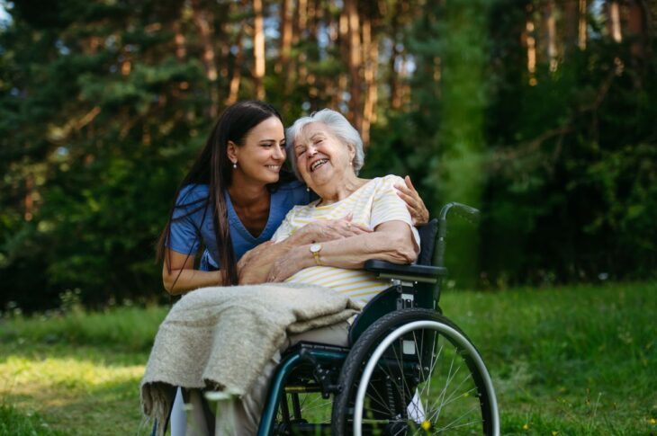 Home nurse taking care of elderly woman in wheelchair