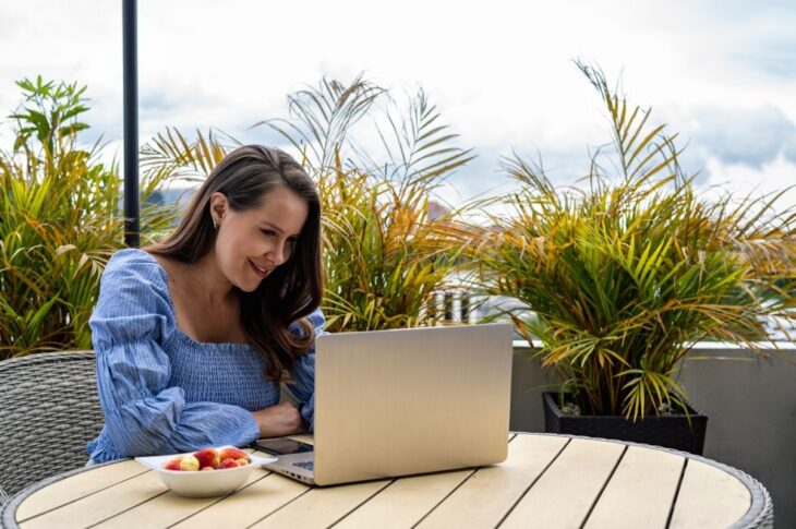 Young woman using laptop and smartphone in the backyard